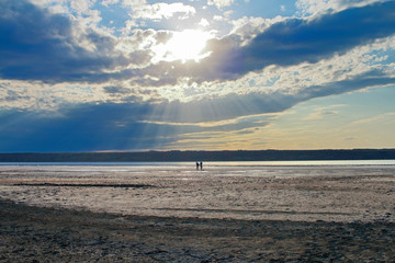 Walk along the coast of the estuary under a cloudy sky.