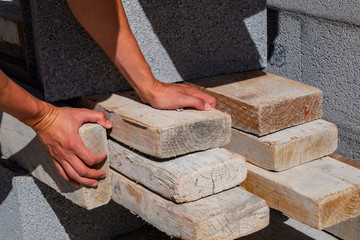 male hands hold wooden bars at a construction site