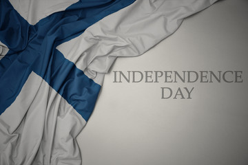 waving colorful national flag of finland on a gray background with text independence day.