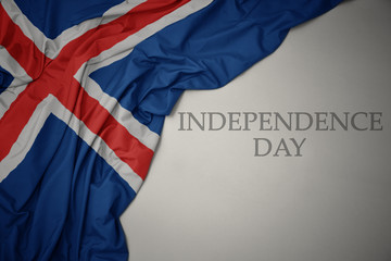 Fototapeta premium waving colorful national flag of iceland on a gray background with text independence day.
