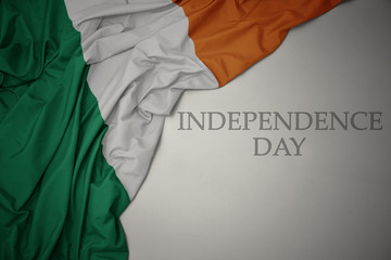 waving colorful national flag of ireland on a gray background with text independence day.