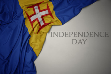 waving colorful national flag of madeira on a gray background with text independence day.