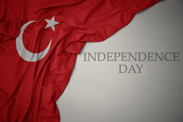 waving colorful national flag of turkey on a gray background with text independence day. - obrazy, fototapety, plakaty