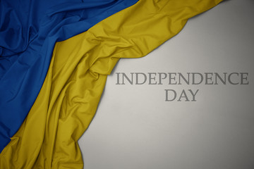 waving colorful national flag of ukraine on a gray background with text independence day.