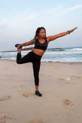 Young African lady doing a stretch on the beach