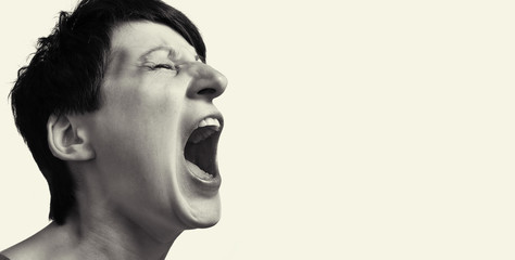 Concept of anger. Portrait of a screaming woman on isolated background with free space. Black and white image.