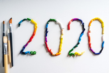 The number 2020 are painted on white canvas with bright oil paints. Top view close up.