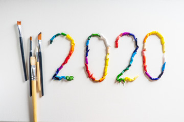 The number 2020 are painted on white canvas with bright oil paints. Top view close up.