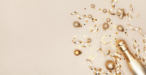 Celebration Christmas background with golden champagne bottle, holiday decoration, confetti stars. Flat lay style. © juliasudnitskaya