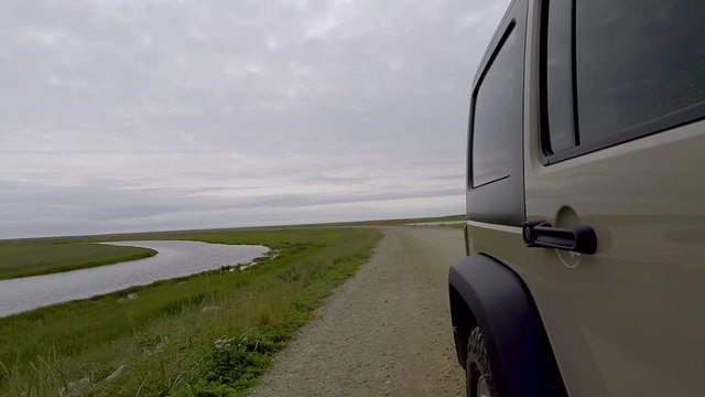 Side shot of a jeep driving  off-road in Nome, Alaska.