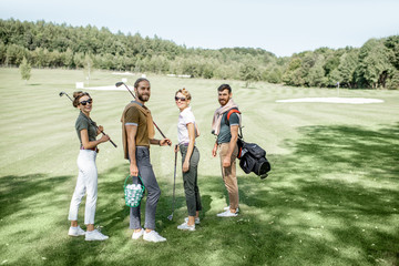 Young and elegant friends walking with golf equipment, hanging out together before the golf play on...