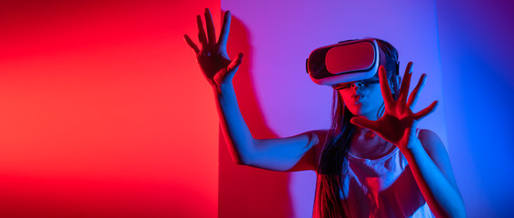 Young woman using glasses of virtual reality on dark background. Smartphone using with VR headset,virtual reality,future technology concept.Asian woman using VR glasses in colorful neon lights.