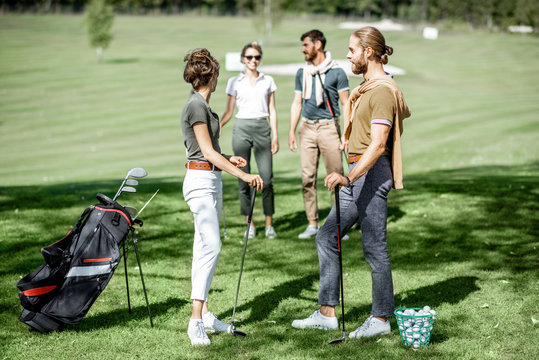 Young elegant friends meeting on the golf course before the play, having fun together on a sunny day - Powered by Adobe
