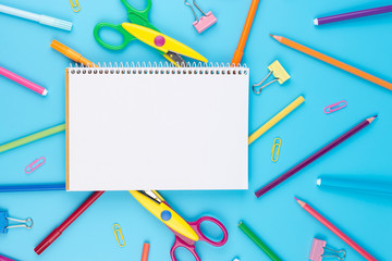 Colorful school supplies and notepadon a blue background. School notebook and various colored stationery. Back to school concept.