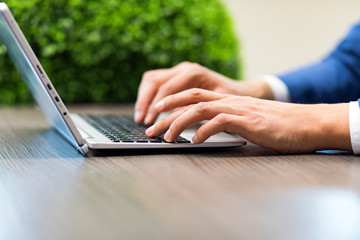 Closeup of a man typing on a laptop keyboard