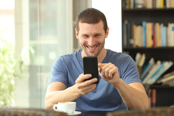 Fototapeta na wymiar Front view of a happy man using phone in a bar