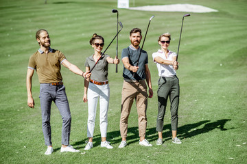 Portrait of a young group of friends keeping golf putters together as a team players on the golf...