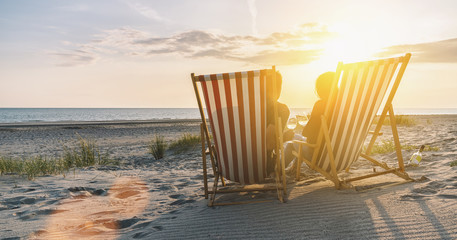Happy Romantic Couple Enjoying Beautiful Sunset at the Beach and toasting with wine