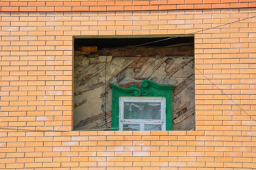 Old house with old green window inside brick and new house. Home under construction