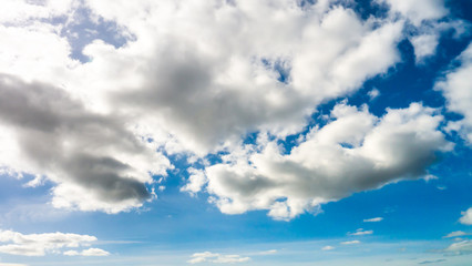 Obraz na płótnie Canvas Vibrant blue sky background with white fluffy clouds taken on a warm spring/summer day.