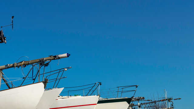 Front of White Sail Boats placed consecutively next to each other with their masts down at Sunderland Marina, Tyne and Wear, England UK.  Image taken on a warm sunny day with a cloudless sky.