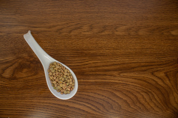  white ceramic spoon with lentils on oak table