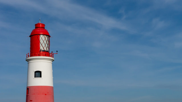 Souter Lighthouse, at Marsden Bay, South Shields, Tyne and Wear, England UK. With blue sky background and clouds.  Image shows red top of lighthouse with light lenses.