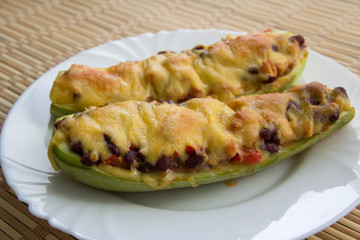 Zucchini boat with chicken, beans and vegetables under cheese