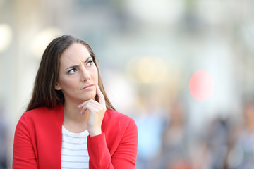 Doubtful woman wondering looking at side in the street