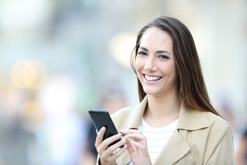 Happy woman holds a smart phone looking at camera