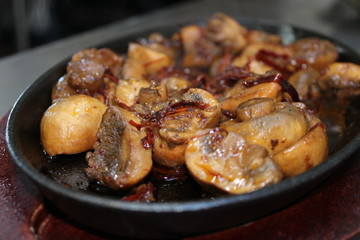 Sauteed mushrooms in butter with garlic and chili on iron and wood plate