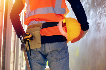 Worker at the construction site, Worker holding a helmet,construction site and sunset background, young professional engineer