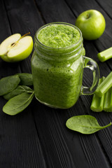 Green smoothies with spinach, apple and celery  on the black wooden background. Location vertical. Copy space.
