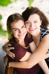 close up portrait of mother and daughter hugging on a bench in the park