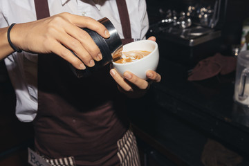 Barista making a cup of coffee latte art in coffee shop