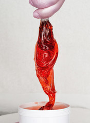 Beautician takes red transparent sugaring paste from a white can