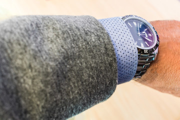 man's arm showing steel watch with shirt and jacket