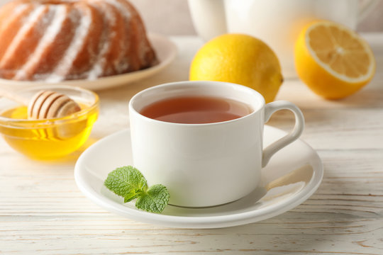 Cup of tea, lemon, mint, honey, dipper and pie on wooden background, close up