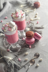 Obraz na płótnie Canvas Pink hot chocolate winter drink with whipped cream and marshmallows. Macaroons and lights