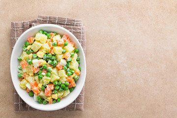 Fresh homemade vegetarian Russian or Olivier salad of potato, carrot, pea, hard-boiled egg and mayonnaise dressing, photographed overhead with copy space on the side (Selective Focus on the salad)