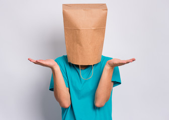 Portrait of teen boy with paper bag over head showing helpless gesture with hands - I do not know....