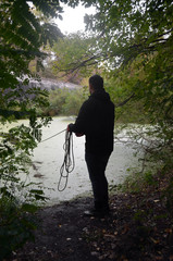 A young man examines the bottom of a pond with a neodym search magnet. Near old tunnel of Stalin....