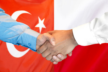 Handshake on Turkey and Poland flag background.