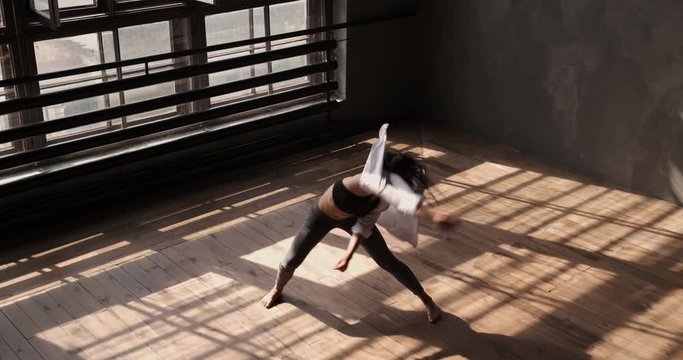 Enjoying modern dance. Girl dancing in studio with large windows and beautiful sunlight. Dance movement. Woman with long hair dancing contemporary freestyle. Graceful dancer pirouettes