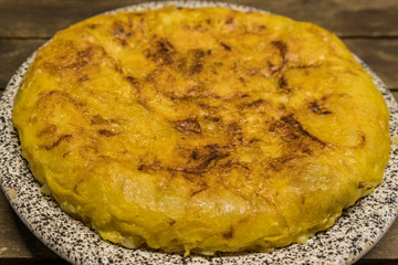 vegan Spanish omelette with potatoes onion and garlic, isolated in a wooden table