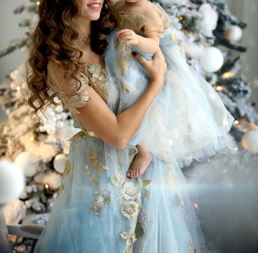 Mom And Baby In Blue Outfit Dresses Near The Christmas Tree With Gifts