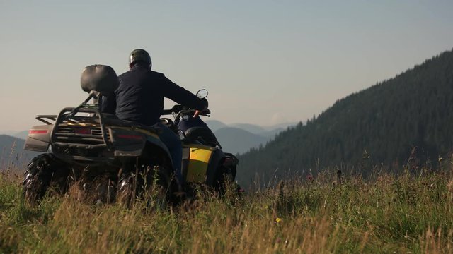 Men driving quad bikes in the mountain. People having fun on nature background.