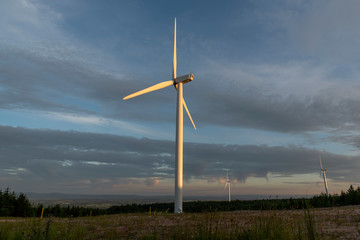 Fototapeta na wymiar solitary wind turbine, lit by the setting sun on the mountainside