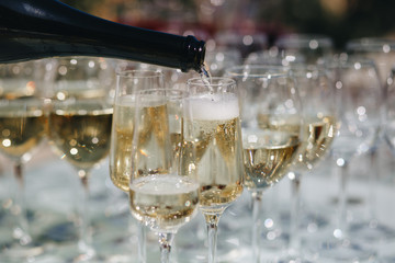 he waiter pours champagne in glasses on the street - wedding catering - look from below