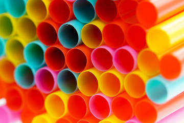 A pile of colourful plastic straws on white background